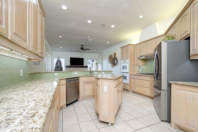 kitchen featuring appliances with stainless steel finishes, light brown cabinetry, tasteful backsplash, a center island, and ceiling fan