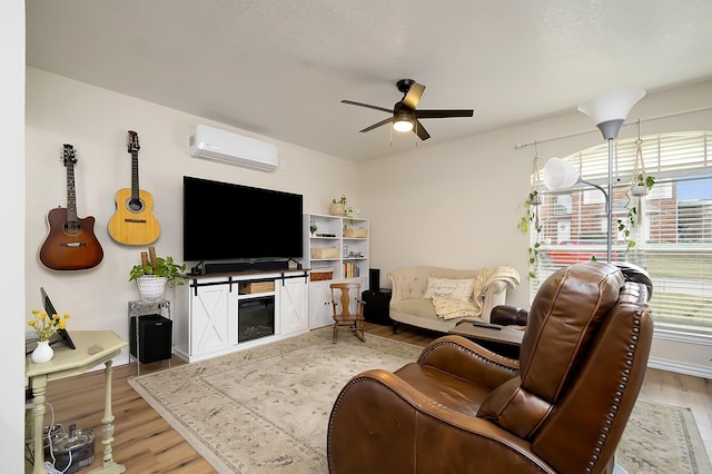 living room with ceiling fan, light wood-type flooring, and an AC wall unit