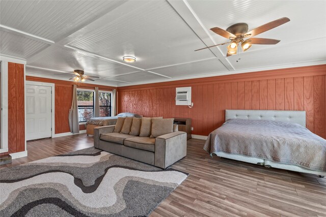 bedroom featuring ceiling fan, wood walls, wood-type flooring, and an AC wall unit