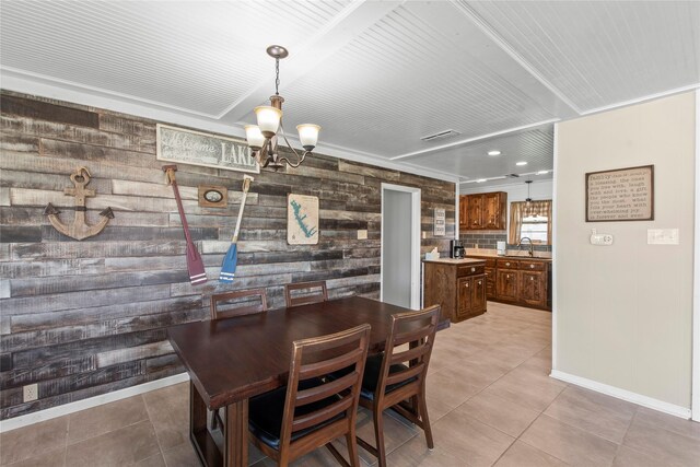 dining space featuring a chandelier, light tile patterned floors, wooden walls, and sink