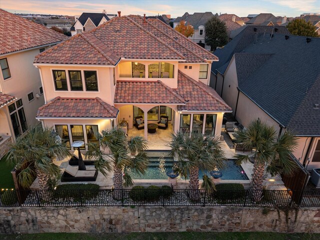 back house at dusk featuring a patio area