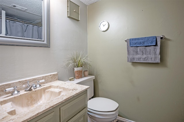 bathroom with a textured ceiling, vanity, and toilet