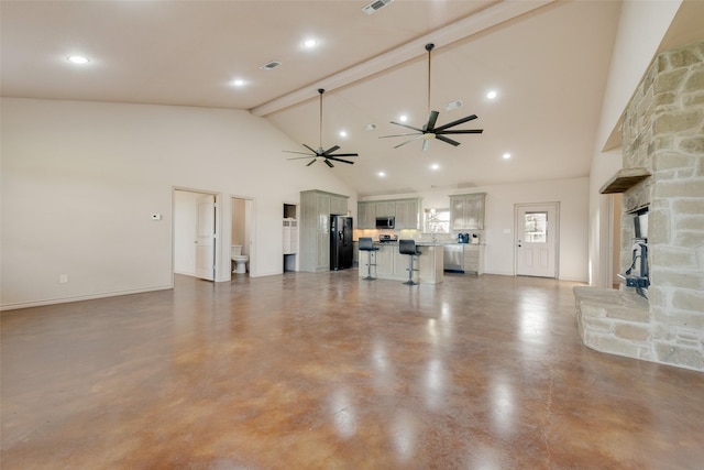 unfurnished living room featuring beamed ceiling, ceiling fan, a stone fireplace, and high vaulted ceiling