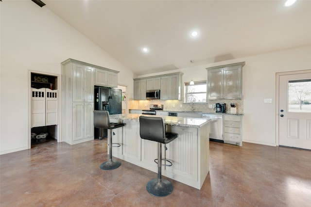 kitchen with gray cabinetry, a breakfast bar, a center island, lofted ceiling, and appliances with stainless steel finishes