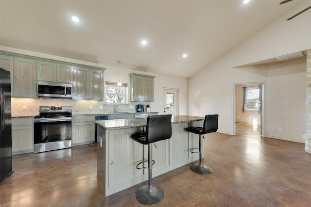 kitchen with light stone countertops, stainless steel appliances, decorative light fixtures, a center island, and lofted ceiling