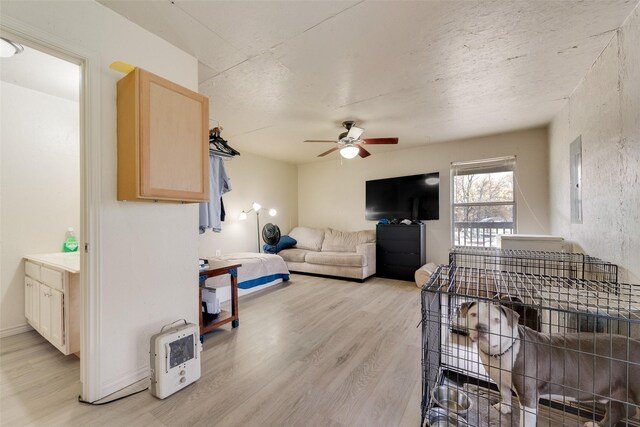 living room with electric panel, light hardwood / wood-style floors, and ceiling fan