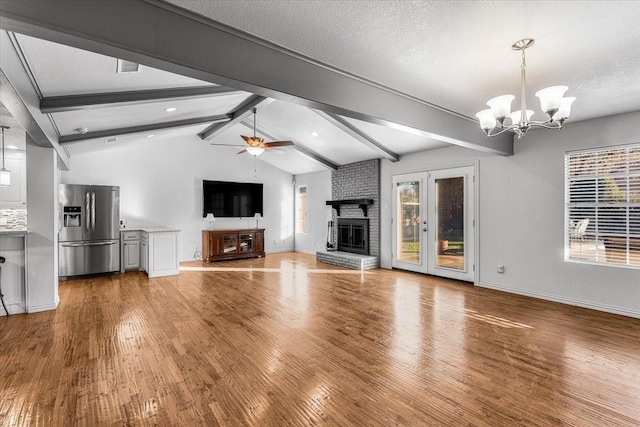 unfurnished living room with ceiling fan with notable chandelier, a healthy amount of sunlight, and a textured ceiling