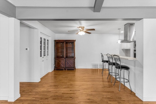 dining space with ceiling fan, beam ceiling, and wood-type flooring