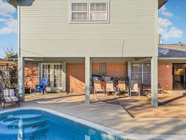 rear view of house with an outdoor pool, a patio area, and brick siding