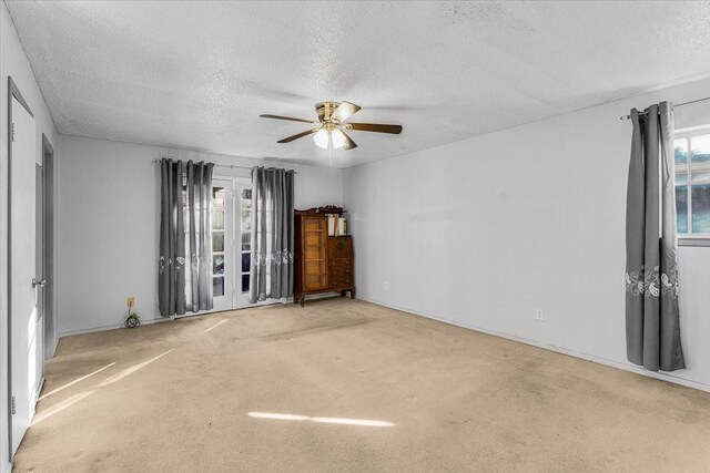 carpeted spare room featuring ceiling fan and a textured ceiling