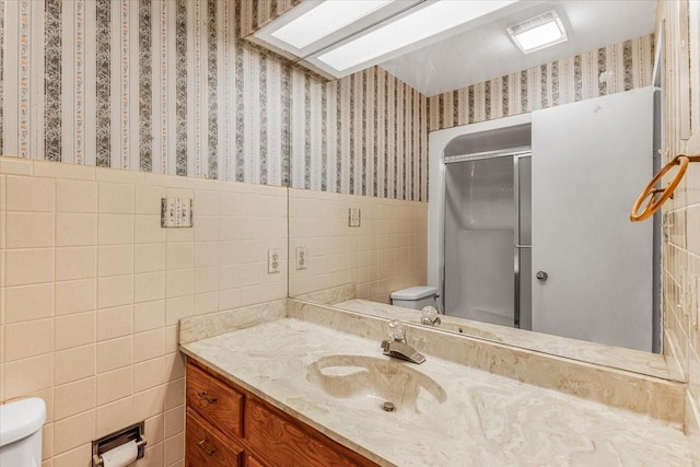 bathroom featuring vanity, toilet, tile walls, and walk in shower