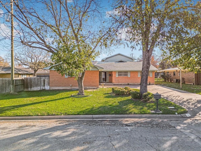 single story home featuring brick siding, fence, a front yard, and concrete driveway