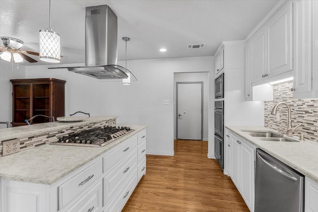 kitchen with light wood-type flooring, island range hood, stainless steel appliances, sink, and decorative light fixtures