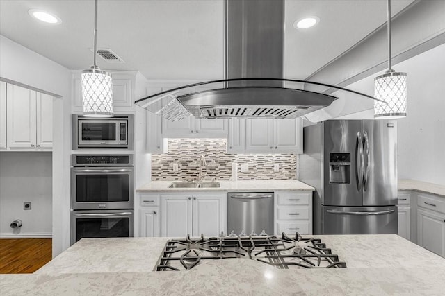 kitchen with appliances with stainless steel finishes, sink, wood-type flooring, white cabinets, and hanging light fixtures