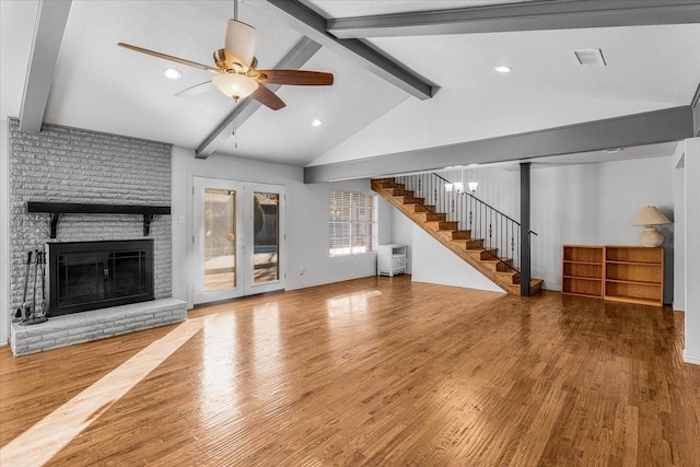 unfurnished living room featuring a fireplace, lofted ceiling with beams, hardwood / wood-style flooring, and ceiling fan with notable chandelier