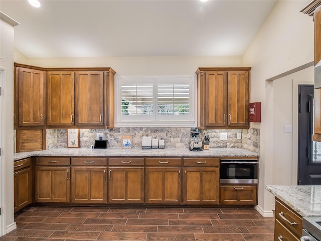 kitchen with light stone counters, dark wood-type flooring, vaulted ceiling, and appliances with stainless steel finishes