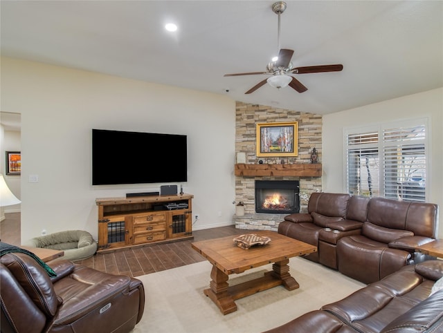 living room with hardwood / wood-style flooring, ceiling fan, a stone fireplace, and lofted ceiling