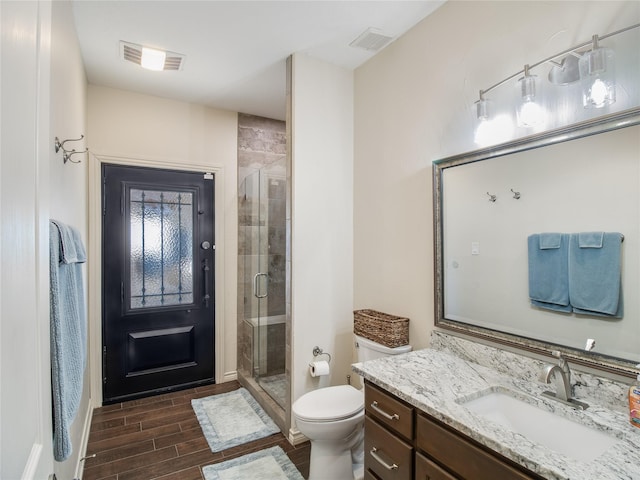 bathroom featuring hardwood / wood-style floors, vanity, an enclosed shower, and toilet