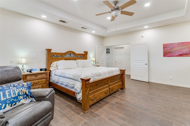 bedroom with a tray ceiling, ceiling fan, and hardwood / wood-style flooring