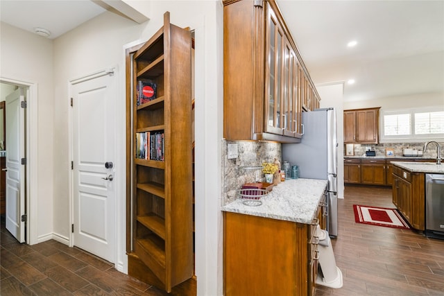 kitchen with dark wood-type flooring, sink, decorative backsplash, appliances with stainless steel finishes, and light stone counters