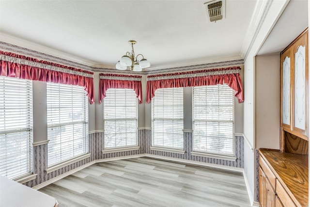 unfurnished dining area with a wealth of natural light, crown molding, a chandelier, and hardwood / wood-style flooring