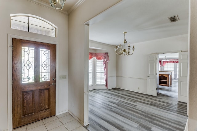 entryway with a chandelier, crown molding, light hardwood / wood-style flooring, and a healthy amount of sunlight