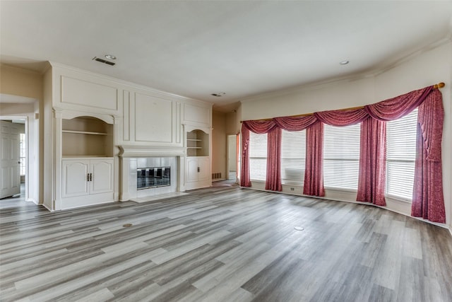 unfurnished living room with crown molding, light hardwood / wood-style flooring, and built in features