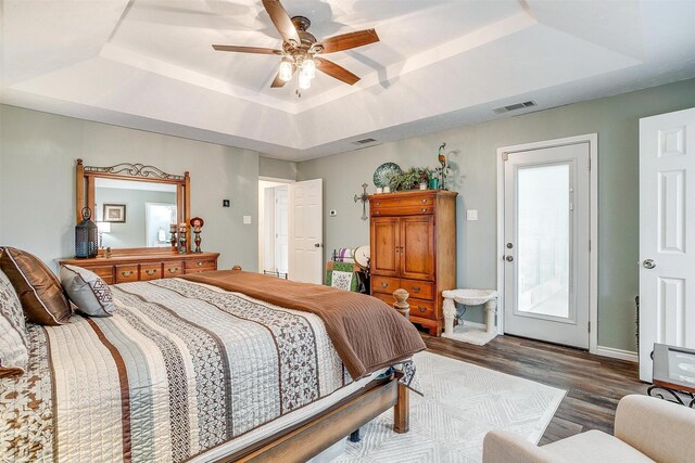 bedroom with a tray ceiling, ceiling fan, and dark hardwood / wood-style floors