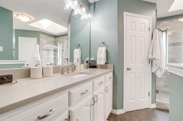 bathroom with tile patterned floors, vanity, tiled shower, and a skylight