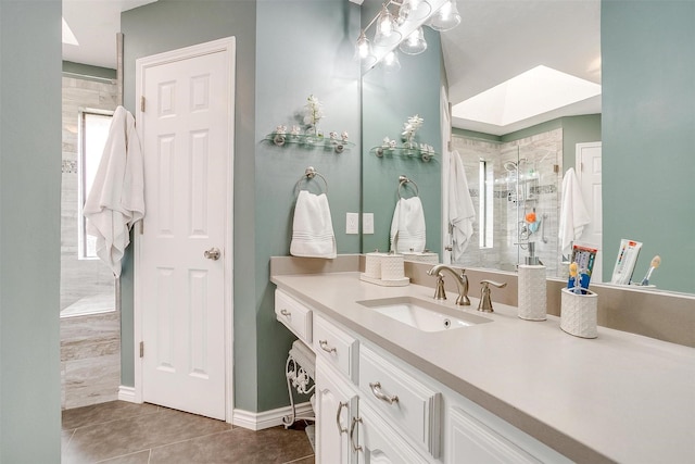 bathroom with tile patterned floors, plenty of natural light, vanity, and tiled shower