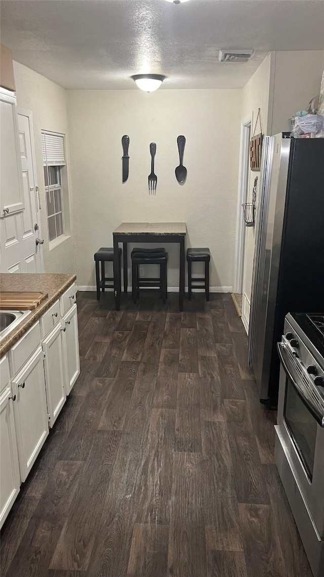 kitchen with dark hardwood / wood-style floors, stainless steel range oven, and white cabinetry