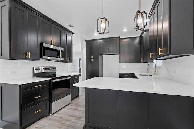 kitchen featuring sink, stainless steel appliances, backsplash, light hardwood / wood-style floors, and decorative light fixtures