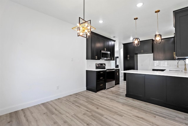 kitchen featuring pendant lighting, sink, appliances with stainless steel finishes, and light hardwood / wood-style flooring