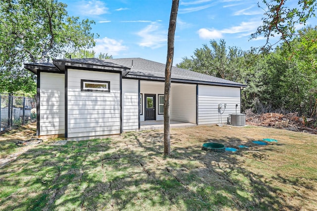 rear view of property with central AC unit, a patio area, and a yard