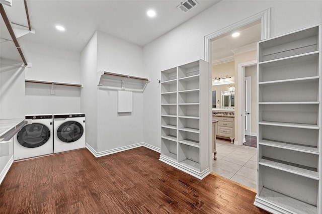 laundry room with wood-type flooring, crown molding, and washing machine and clothes dryer