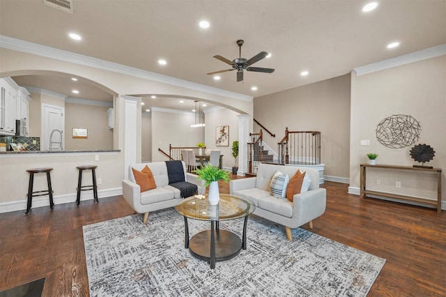 living room featuring crown molding, dark hardwood / wood-style flooring, ceiling fan, and sink