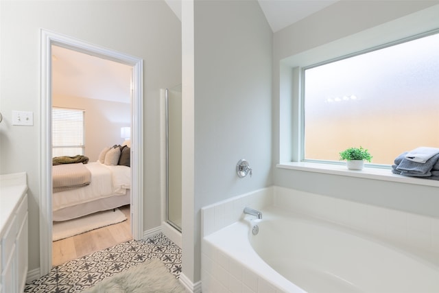 bathroom featuring vaulted ceiling, a wealth of natural light, and independent shower and bath