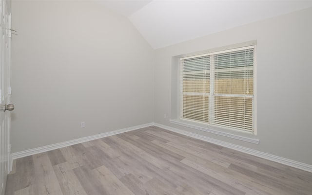 spare room featuring light hardwood / wood-style floors and vaulted ceiling