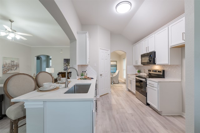 kitchen featuring tasteful backsplash, stainless steel range with electric stovetop, vaulted ceiling, sink, and white cabinetry