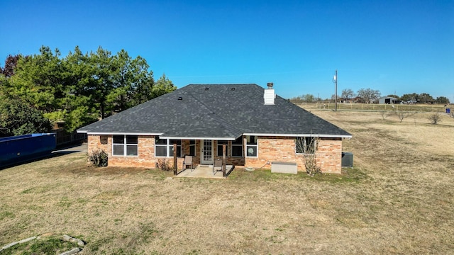 rear view of property with cooling unit, a yard, and a patio