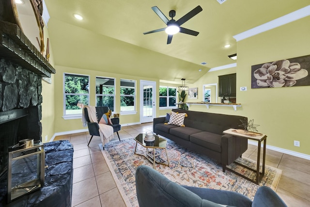 tiled living room with ceiling fan, a stone fireplace, and vaulted ceiling