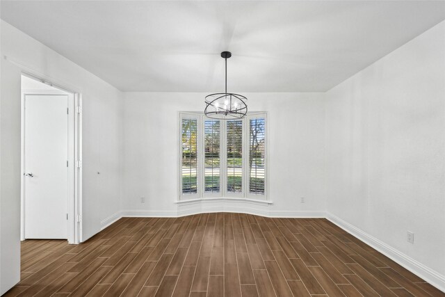 unfurnished dining area with dark wood-type flooring and a notable chandelier