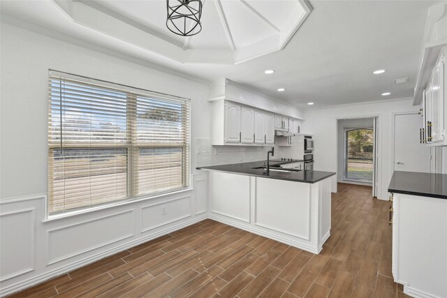 kitchen featuring decorative backsplash, dark wood-type flooring, sink, pendant lighting, and white cabinetry