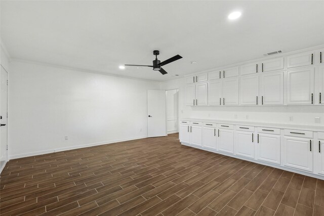 unfurnished living room featuring ceiling fan, crown molding, and dark wood-type flooring