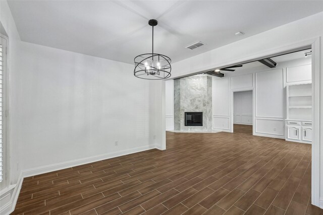 unfurnished living room featuring a high end fireplace, dark hardwood / wood-style floors, and an inviting chandelier