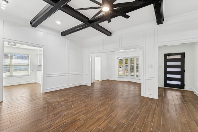 unfurnished living room with beamed ceiling, ceiling fan with notable chandelier, dark wood-type flooring, and coffered ceiling