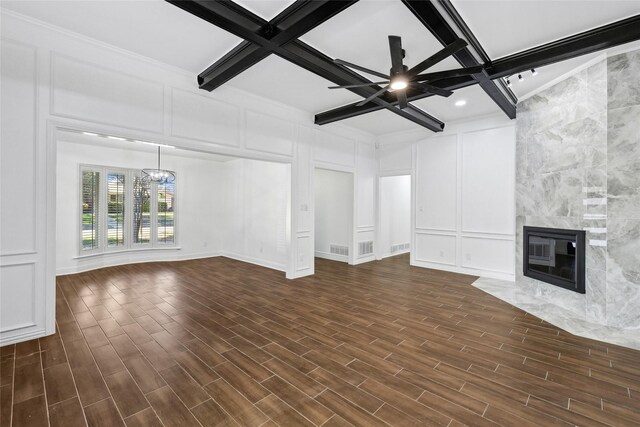 unfurnished living room featuring dark hardwood / wood-style flooring, coffered ceiling, ceiling fan with notable chandelier, beamed ceiling, and a fireplace