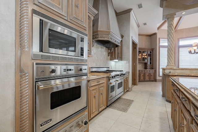 kitchen with premium range hood, ornamental molding, ornate columns, stainless steel appliances, and a chandelier