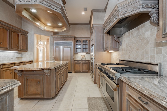 kitchen featuring light stone counters, custom range hood, premium appliances, crown molding, and light tile patterned flooring