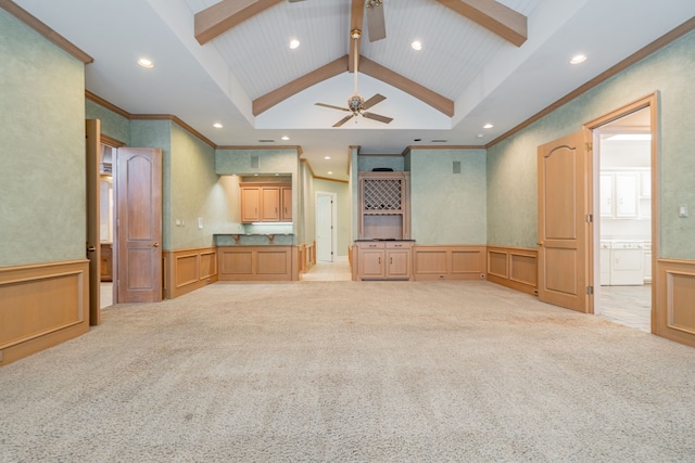 unfurnished living room with ceiling fan, lofted ceiling with beams, light colored carpet, and ornamental molding